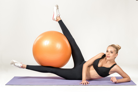 Young blonde woman training with fitball on the mat. Fitness exercisesの写真素材