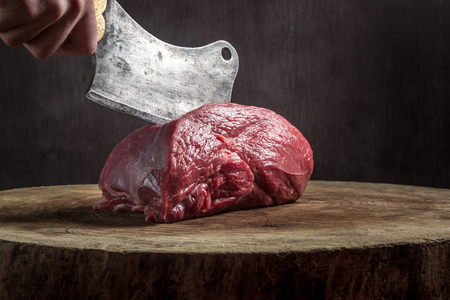 butcher cuts meat. old hatchet and impressive wooden baseの写真素材