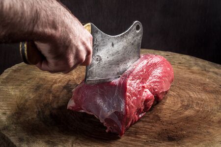 butcher cuts meat. old hatchet and impressive wooden baseの写真素材