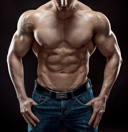 Muscular bodybuilder guy doing posing over black background. Naked torso in jeans. Close-upの写真素材
