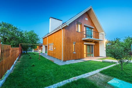 Beautiful wooden house with a lawn. Facade of traditional homes with grass in the foreground. at sunset and sunriseの写真素材