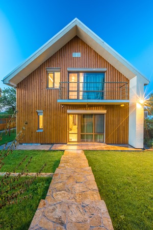 Beautiful wooden house with a lawn. Facade of traditional homes with grass in the foreground. at sunset and sunriseの写真素材