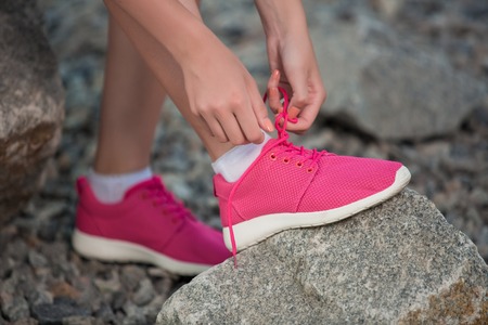 Running shoes - woman tying shoe laces. Closeup of female sport fitness runner getting ready for jogging outdoors on park path in late summer or fall.の写真素材