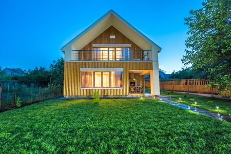 Beautiful wooden house with a lawn. Facade of traditional homes with grass in the foreground. at sunset and sunriseの写真素材