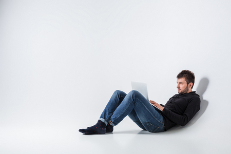 a young man in casual clothes working on a laptop.の写真素材