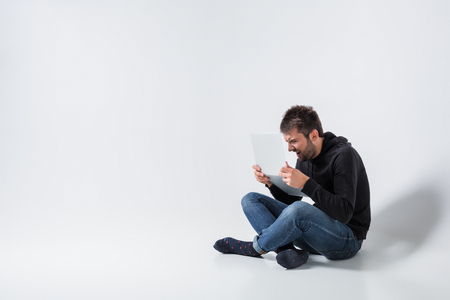 a young man in casual clothes working on a laptop. angry looking at the screenの写真素材