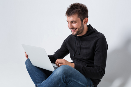 a young man in casual clothes working on a laptop. joyful looking at laptop smilingの写真素材