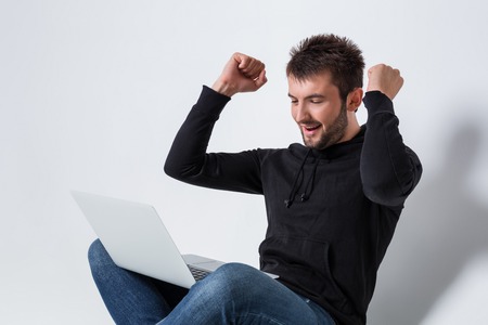 a young man in casual clothes working on a laptop. glad hands upの写真素材