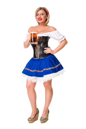 Beautiful young blond girl in dirndl drinks out of oktoberfest beer stein. Isolated on white background. full heightの写真素材