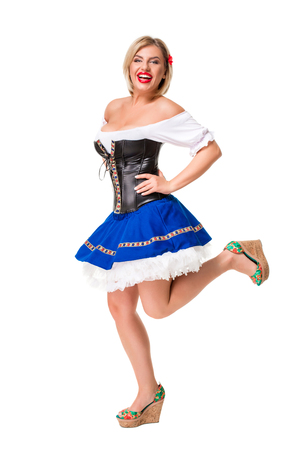 Beautiful young blond girl in dirndl drinks out of oktoberfest beer stein. Isolated on white background. full heightの写真素材