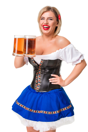 Beautiful young blond girl in dirndl drinks out of oktoberfest beer stein. Isolated on white background.の写真素材