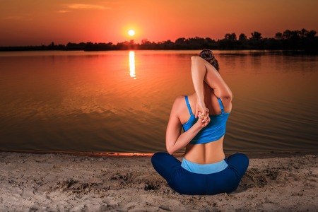 yoga at sunset on the beach. woman doing yoga, performing asanas and enjoying life on the riverの写真素材