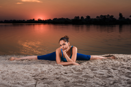yoga at sunset on the beach. woman doing yoga, performing asanas and enjoying life on the riverの写真素材