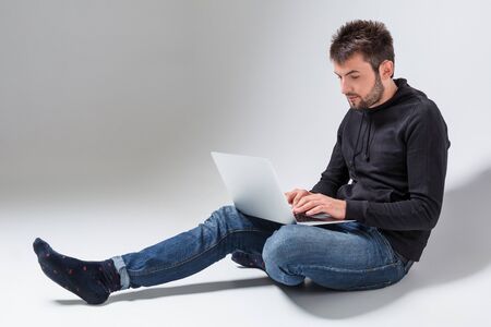 a young man in casual clothes working on a laptop.の写真素材