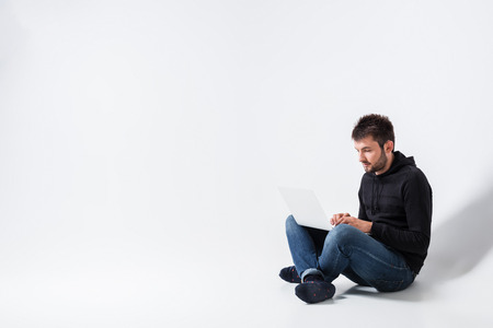 a young man in casual clothes working on a laptop.の写真素材
