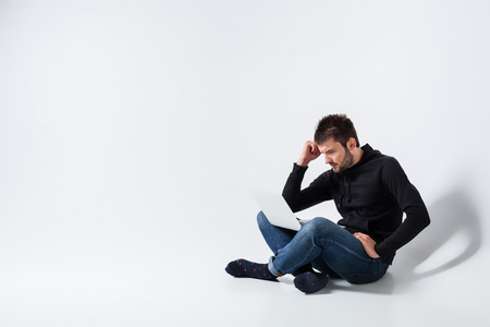 a young man in casual clothes working on a laptop. upset looking at monitorの写真素材