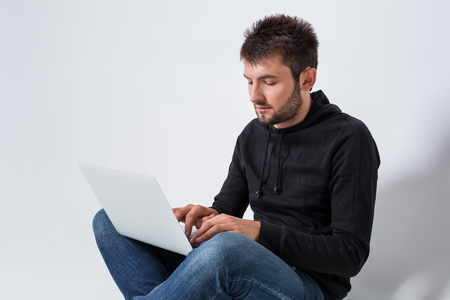 a young man in casual clothes working on a laptop. joyful looking at laptop smilingの写真素材