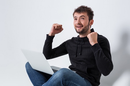 a young man in casual clothes working on a laptop. glad hands upの写真素材