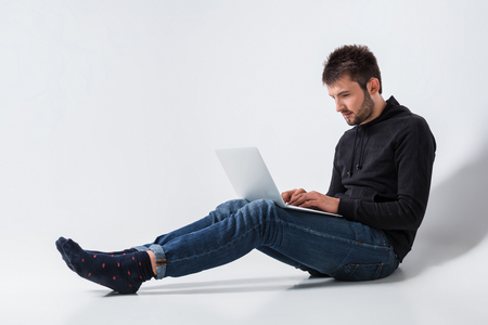 a young man in casual clothes working on a laptop.の写真素材