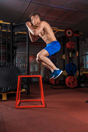 Shirtless man jumping on block. young muscular guy doing exercise jump CrossFitの写真素材