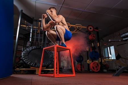 Shirtless man jumping on block. young muscular guy doing exercise jump CrossFitの写真素材