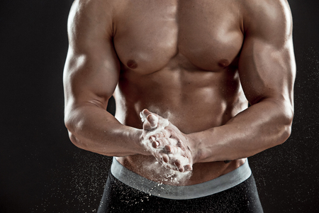 young muscular man preparing to hand lifting heavy weight. White talcum dynamically scatters in different directions. Close-upの写真素材