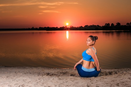 yoga at sunset on the beach. woman doing yoga, performing asanas and enjoying life on the riverの写真素材
