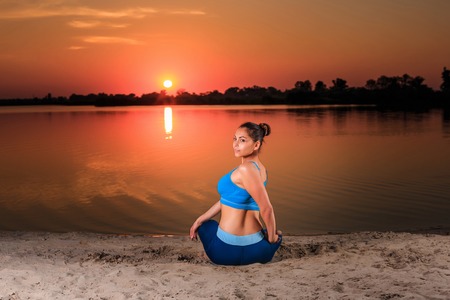 yoga at sunset on the beach. woman doing yoga, performing asanas and enjoying life on the riverの写真素材