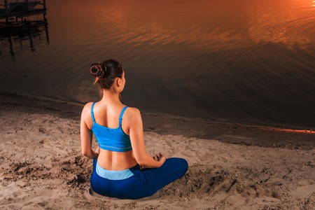 yoga at sunset on the beach. woman doing yoga, performing asanas and enjoying life on the riverの写真素材