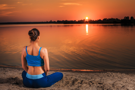 yoga at sunset on the beach. woman doing yoga, performing asanas and enjoying life on the riverの写真素材
