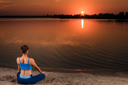 yoga at sunset on the beach. woman doing yoga, performing asanas and enjoying life on the riverの写真素材