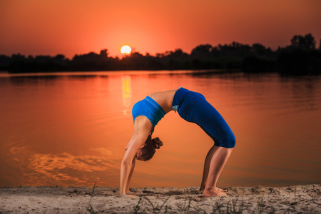 yoga at sunset on the beach. woman doing yoga, performing asanas and enjoying life on the riverの写真素材