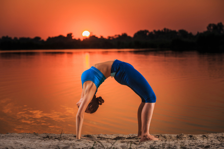 yoga at sunset on the beach. woman doing yoga, performing asanas and enjoying life on the riverの写真素材