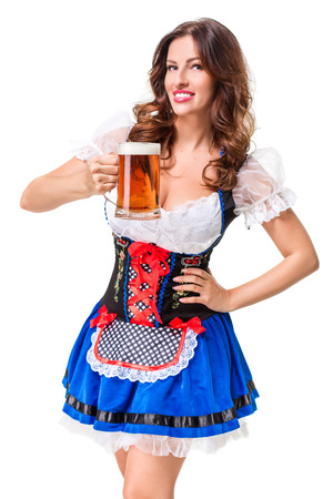 Beautiful young brunette girl in dirndl drinks out of oktoberfest beer stein. Isolated on white background.の写真素材