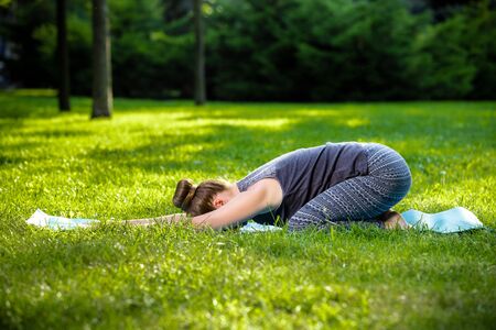 Young fitness woman meditation in a city park.Yoga at sunset in the park. Girl is practicing yoga. Fitness training outdoors. Attractive fitness woman. Workout outdoors. Healthy lifestyleの写真素材