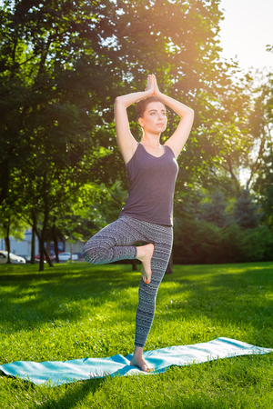 Young fitness woman meditation in a city park.Yoga at sunset in the park. Girl is practicing yoga. Fitness training outdoors. Attractive fitness woman. Workout outdoors. Healthy lifestyle. sun flareの写真素材