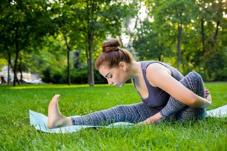 Young fitness woman meditation in a city park.Yoga at sunset in the park. Girl is practicing yoga. Fitness training outdoors. Attractive fitness woman. Workout outdoors. Healthy lifestyleの写真素材