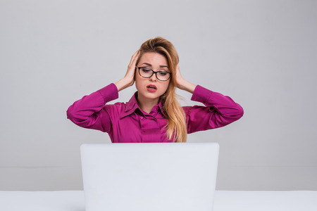 Young businesswoman working at laptop computer. she is going through and looking at the monitor. her head in her handsの写真素材