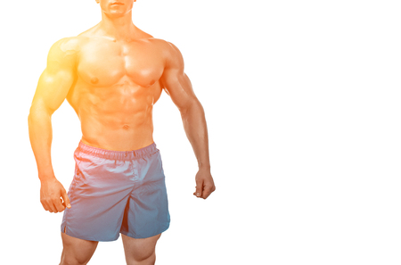 Strong Athletic Man showing muscular body and sixpack abs isolated on white background. with sun flare. Close up, copyspaceの写真素材