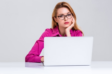 Young businesswoman working at laptop computer. she was tired and looking at cameraの写真素材