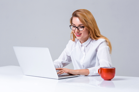 Young businesswoman working at laptop computer. she smiles, prints and looking at monitorの写真素材