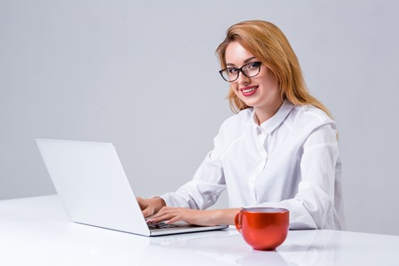Young businesswoman working at laptop computer. she smiles, prints and looking at monitorの写真素材