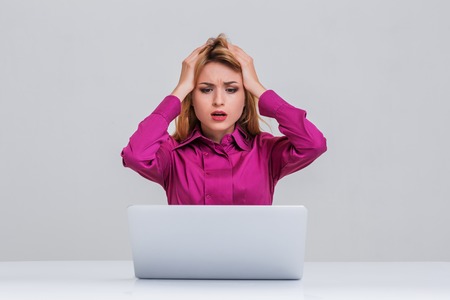Young businesswoman working at laptop computer. she is going through. her head in her handsの写真素材