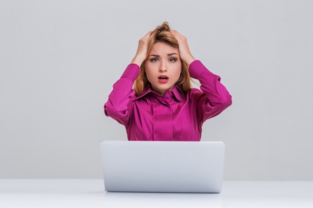 Young businesswoman working at laptop computer. she is going through. her head in her handsの写真素材