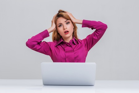 Young businesswoman working at laptop computer. she is going through. her head in her handsの写真素材