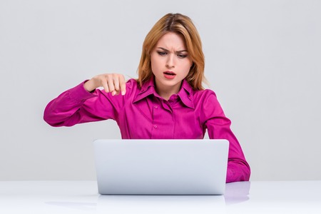 Young businesswoman working at laptop computer. she was surprised, prints and indignation is pointing at the monitorの写真素材