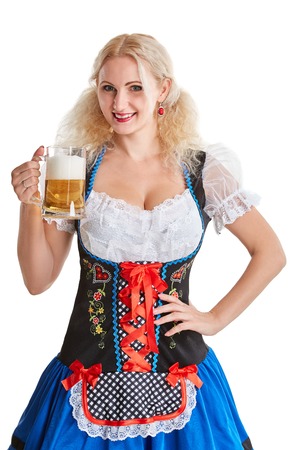 Beautiful young blond girl in dirndl drinks out of oktoberfest beer stein. Isolated on white background. she holds a glass with a drink and smilingの写真素材