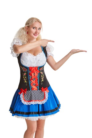 Beautiful young blond girl in dirndl drinks out of oktoberfest beer stein. Isolated on white background. pointing finger and smiling. copyspace desing conceptの写真素材