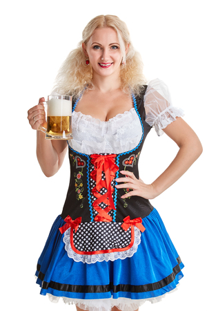 Beautiful young blond girl in dirndl drinks out of oktoberfest beer stein. Isolated on white background. she holds a glass with a drink and smilingの写真素材