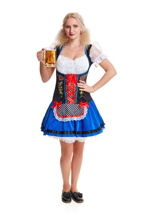 Beautiful young blond girl in dirndl drinks out of oktoberfest beer stein. Isolated on white background. she holds a glass with a drink and smiling. full heightの写真素材